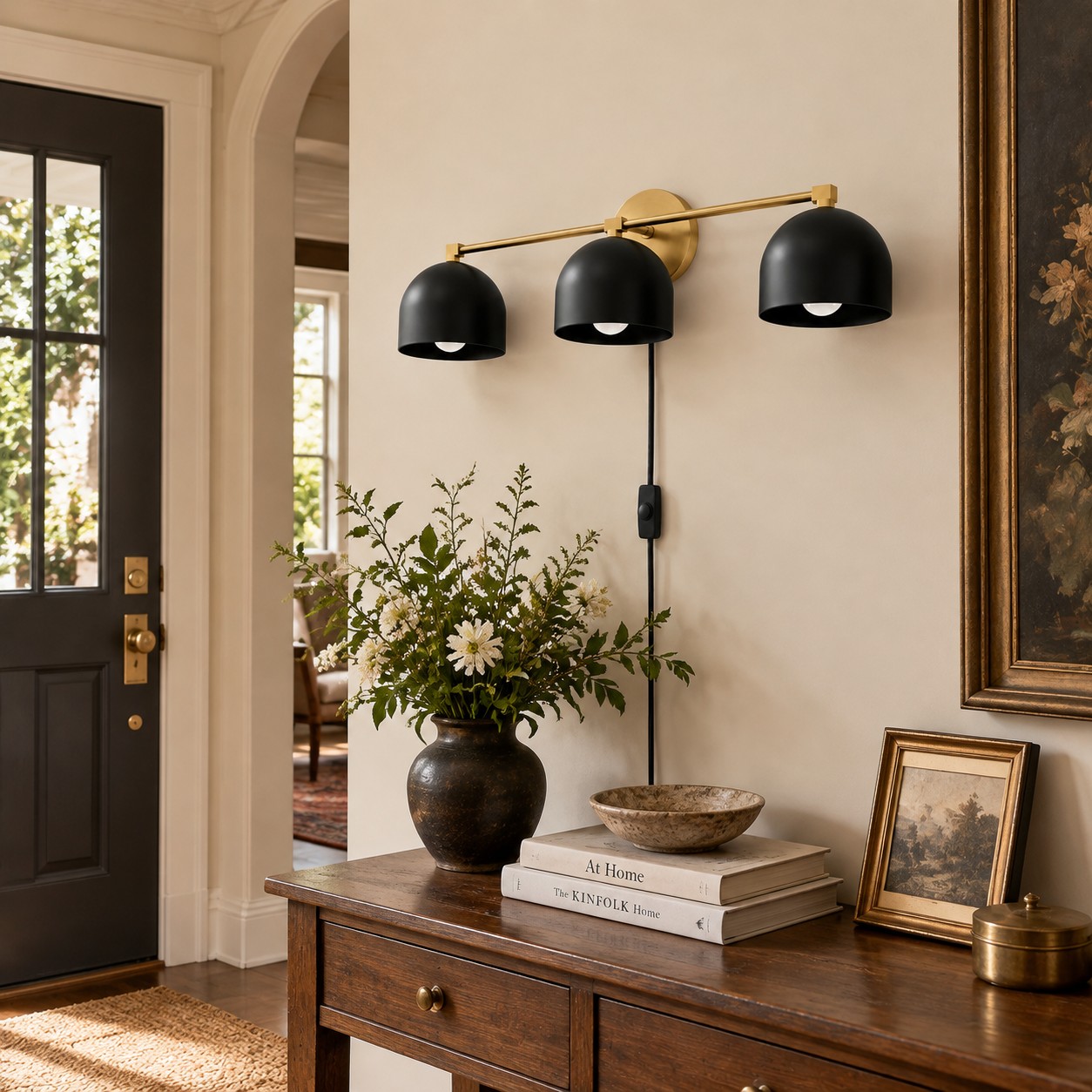 Three black domes on a brass bar above an entry console