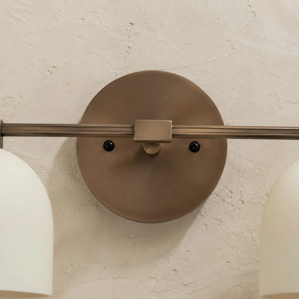 Round metal wall base with two dark screws and the bar across it