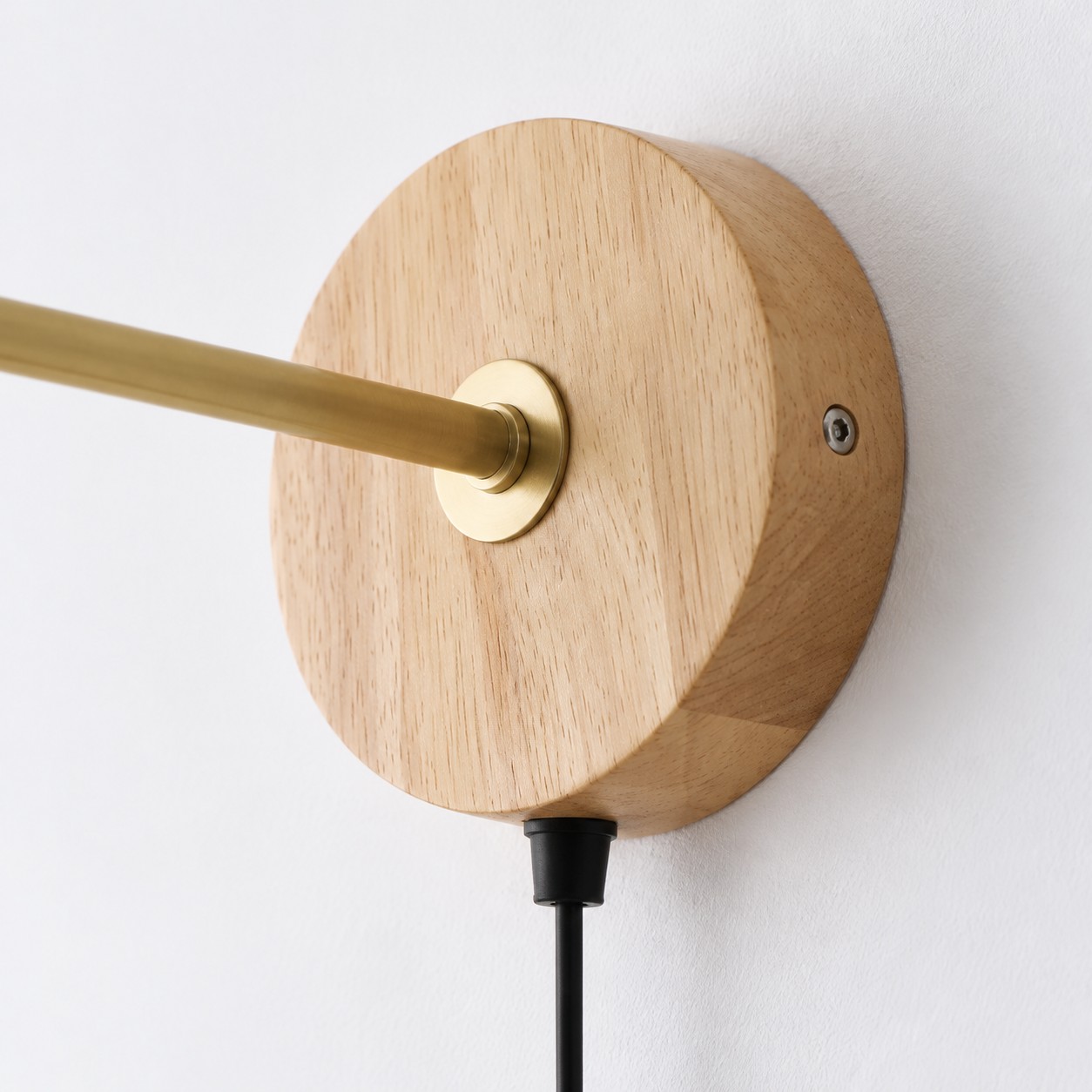Round light wood backplate with a brass arm and black plug-in cord