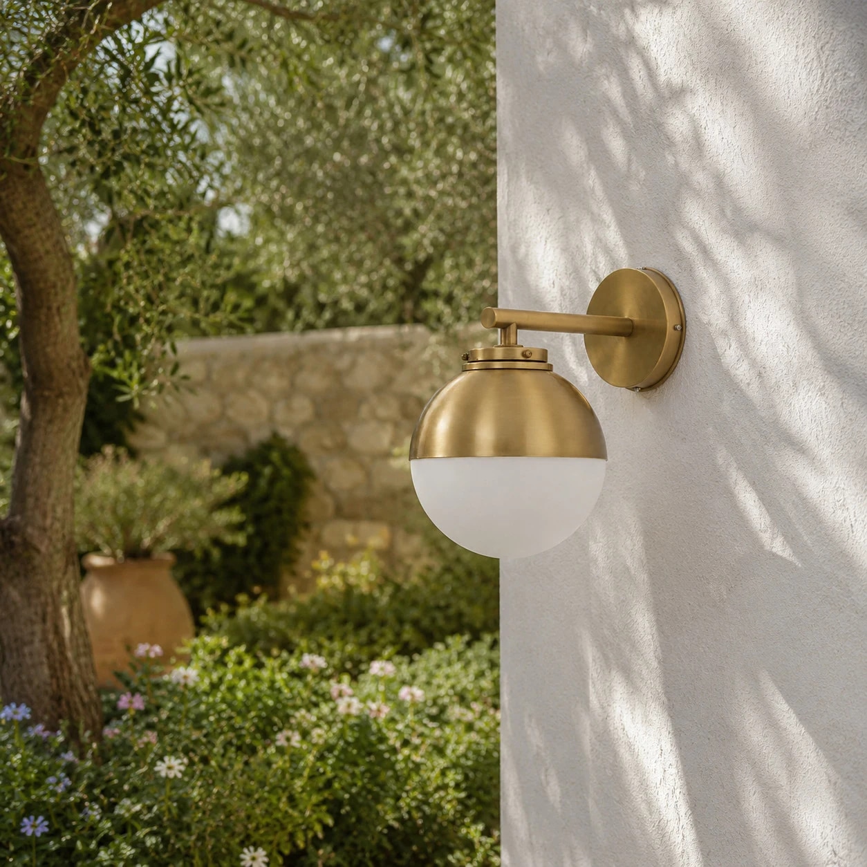 Applique murale vintage en laiton installée sur un mur extérieur blanc de jardin.