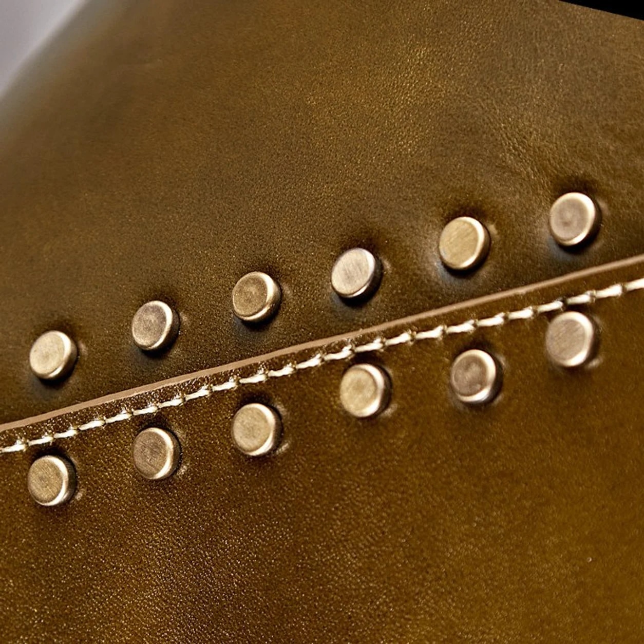Gros plan sur un abat-jour en cuir marron avec des rivets dorés