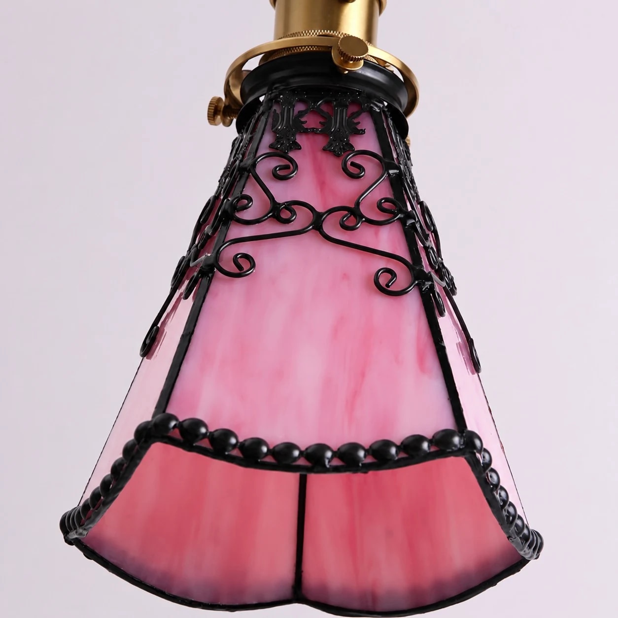 Pink stained glass shade close-up with dark leading and scrollwork