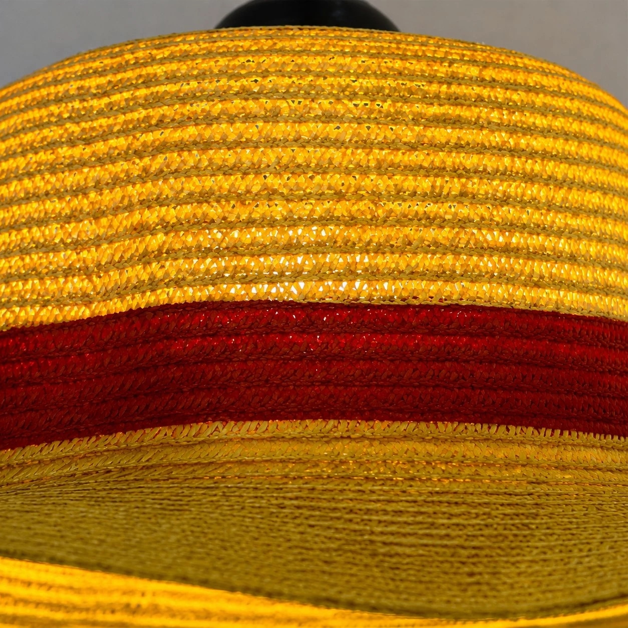 Textura de paja en capas, ala ancha y una elegante banda decorativa roja.
