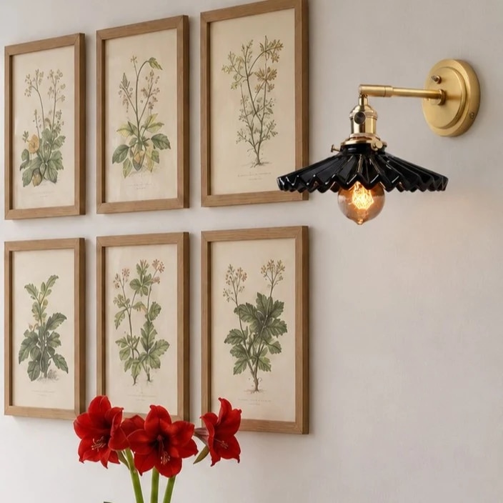 Schwarze Wandleuchte über gerahmter botanischer Kunst