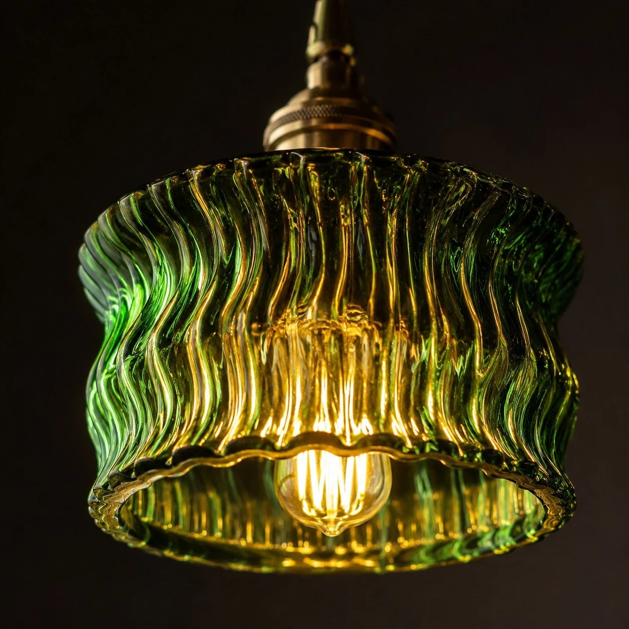 Varmt ljus som lyser genom en grön, krusad glasskärm med pendel