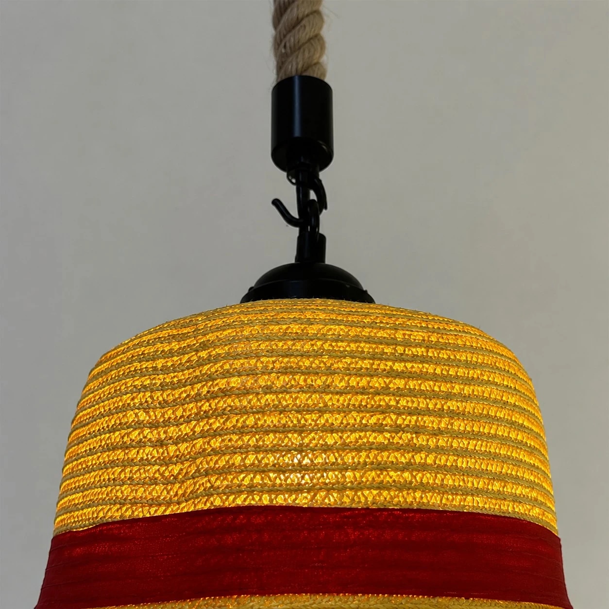 Textura de paja en capas, ala ancha y una elegante banda decorativa roja.