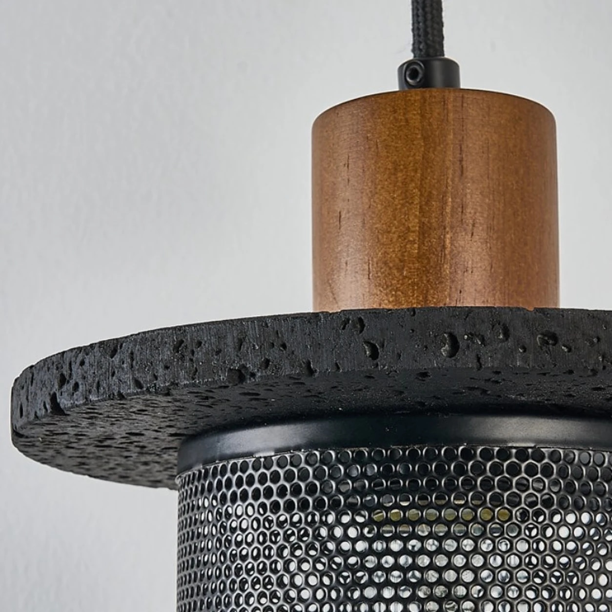Detalle cercano de la conexión entre la tapa de madera y la pantalla de malla negra.