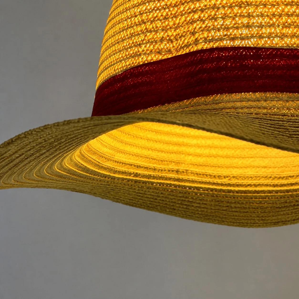 Textura de paja en capas, ala ancha y una elegante banda decorativa roja.
