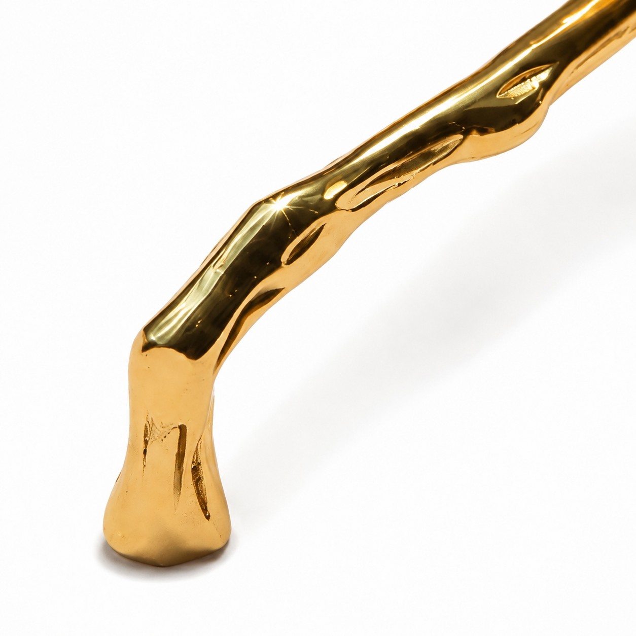 Close view of the polished branch-like brass handle form