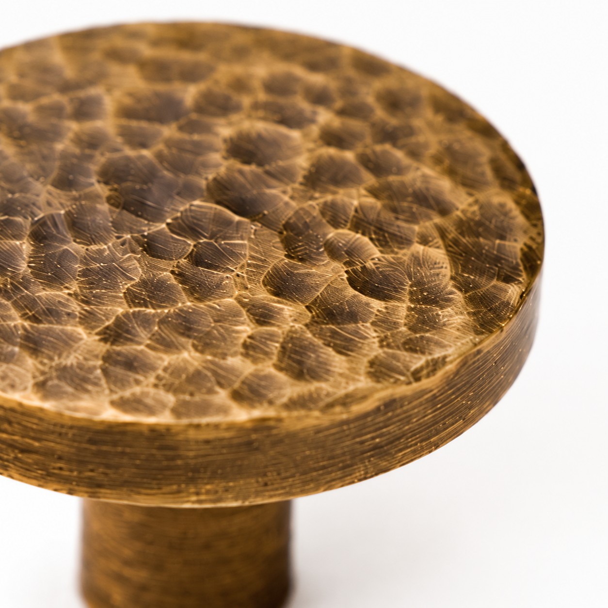 Close view of the hammered Antique Brass flat round knob face and edge