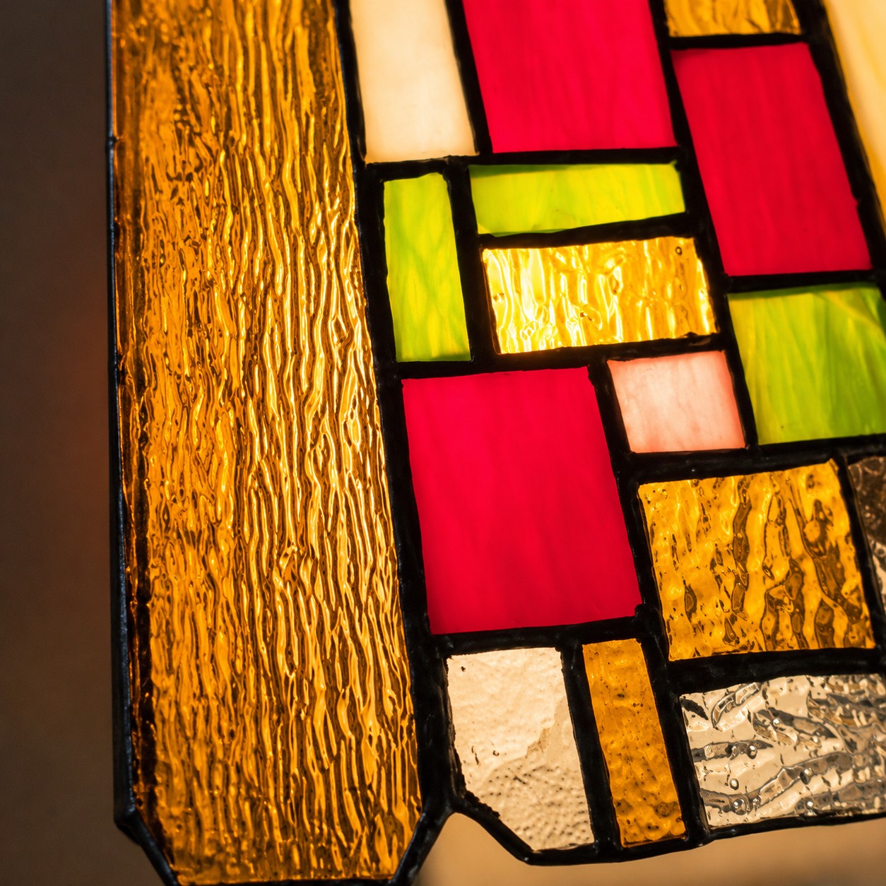 Close view of the pendant's amber, red and green textured glass panels