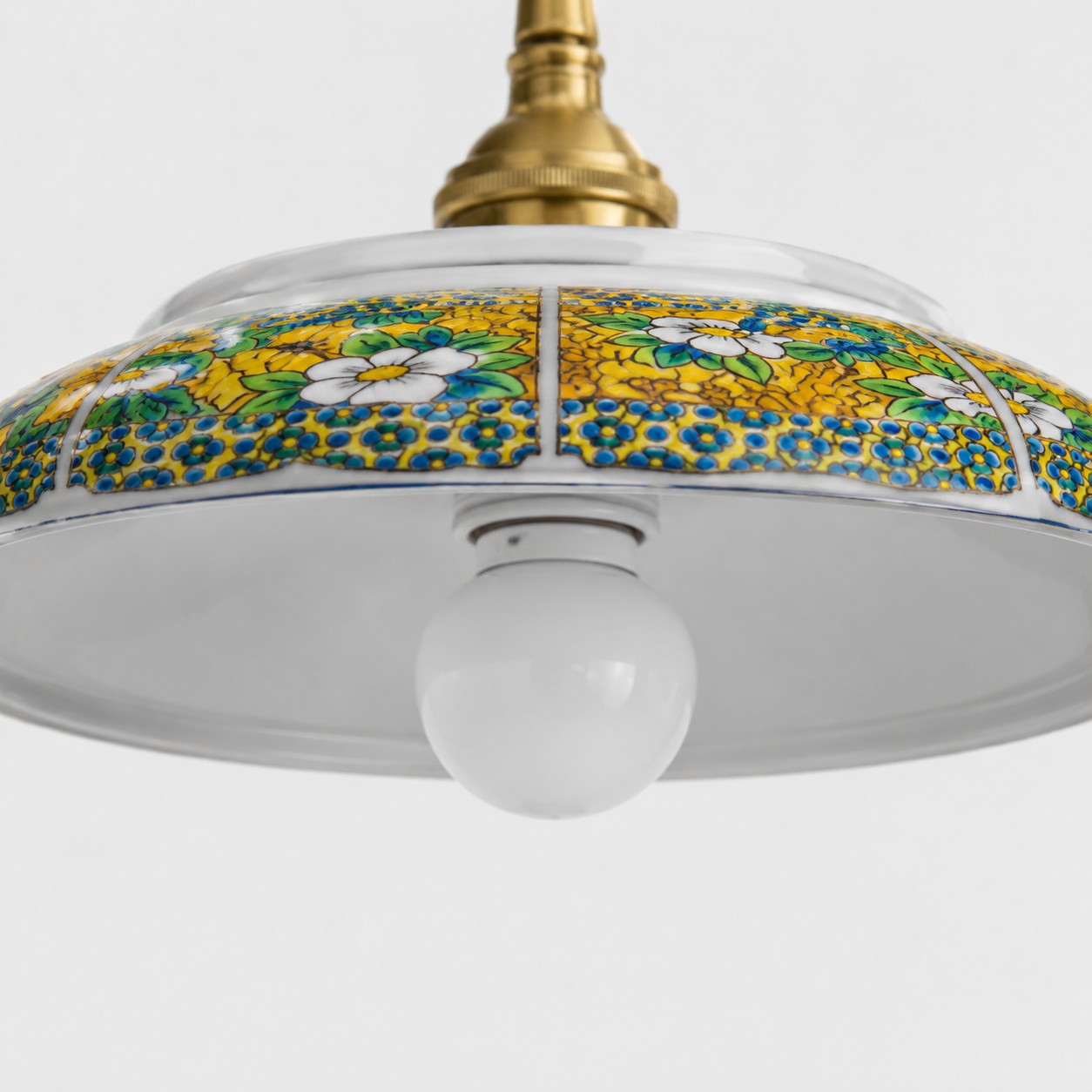 Detailaufnahme des gelben, floralen Keramikschirmmusters und der sichtbaren Glühbirnenöffnung