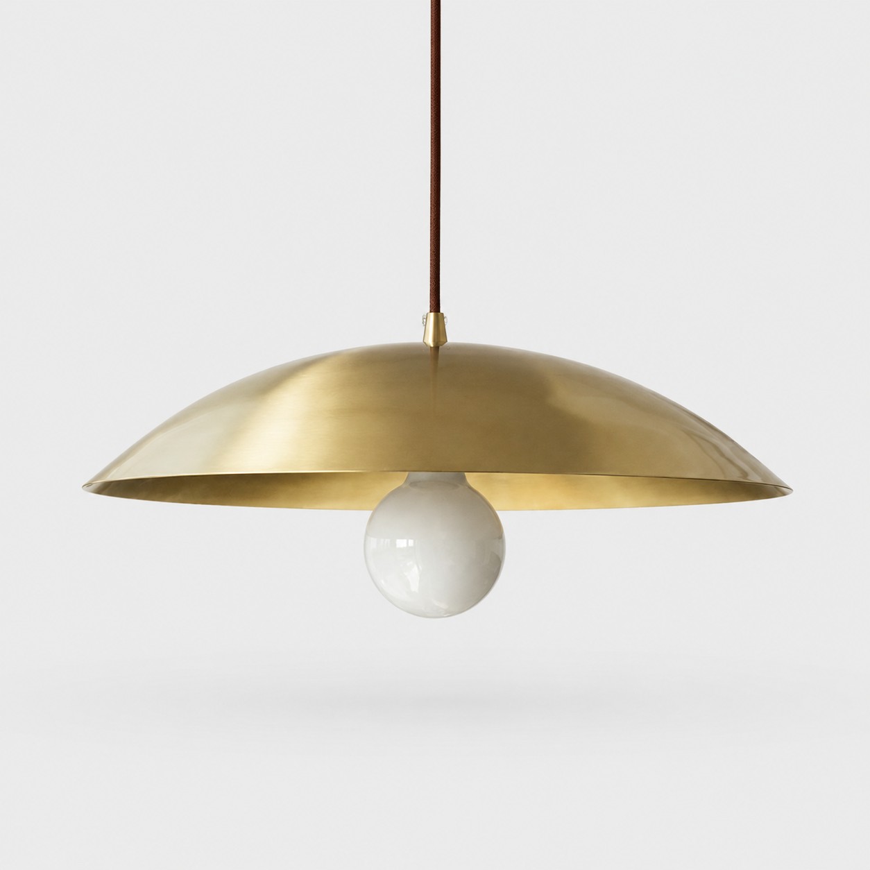 Brushed brass dome pendant light on a neutral gray background