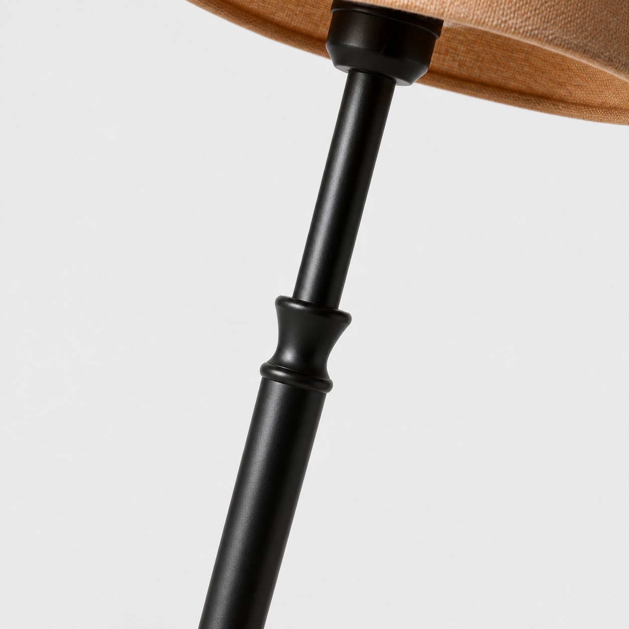 Gros plan sur la jonction entre le pied et l'abat-jour d'un lampadaire en fer noir