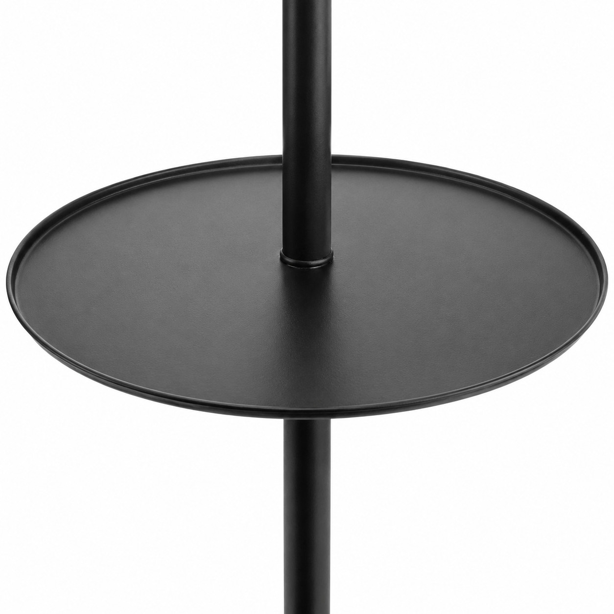 Gros plan sur la table d'appoint ronde noire fixée au pied du lampadaire