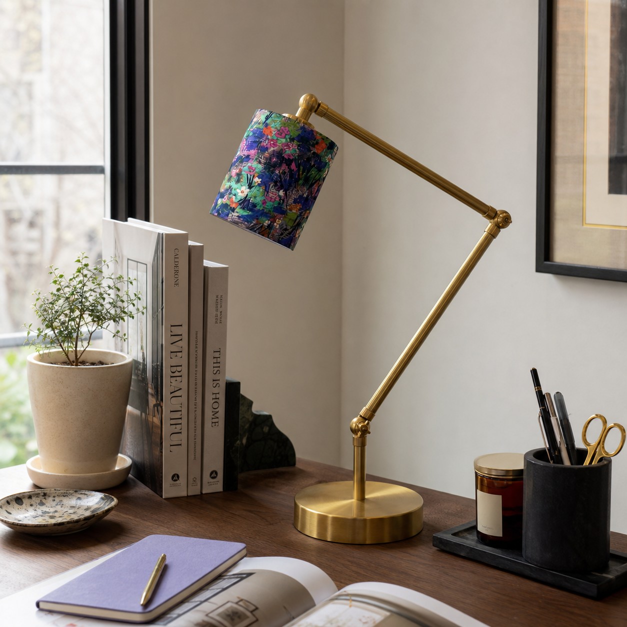 Floral shade table lamp styled on a desk near books and decor