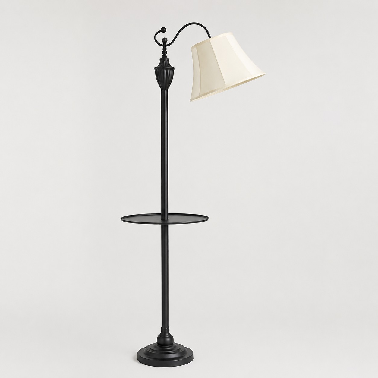 Vue complète d'un lampadaire vintage noir arqué avec abat-jour en tissu beige et table d'appoint ronde
