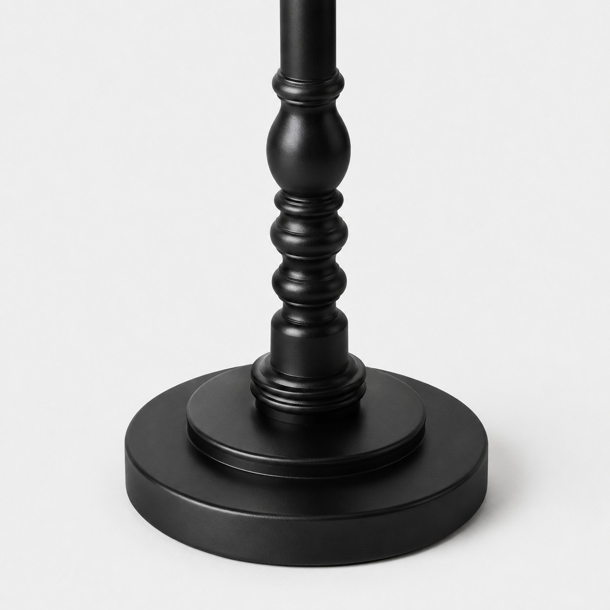 Detailweergave van de zwarte ronde voet en het onderste gedraaide houten detail.
