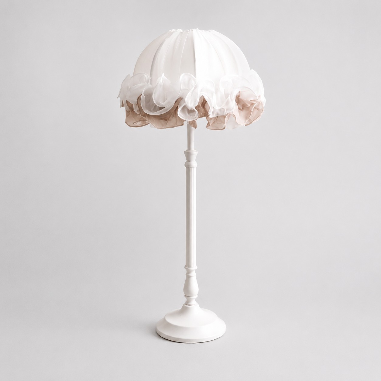 Front view of white ruffled fabric table lamp with sculpted metal stem