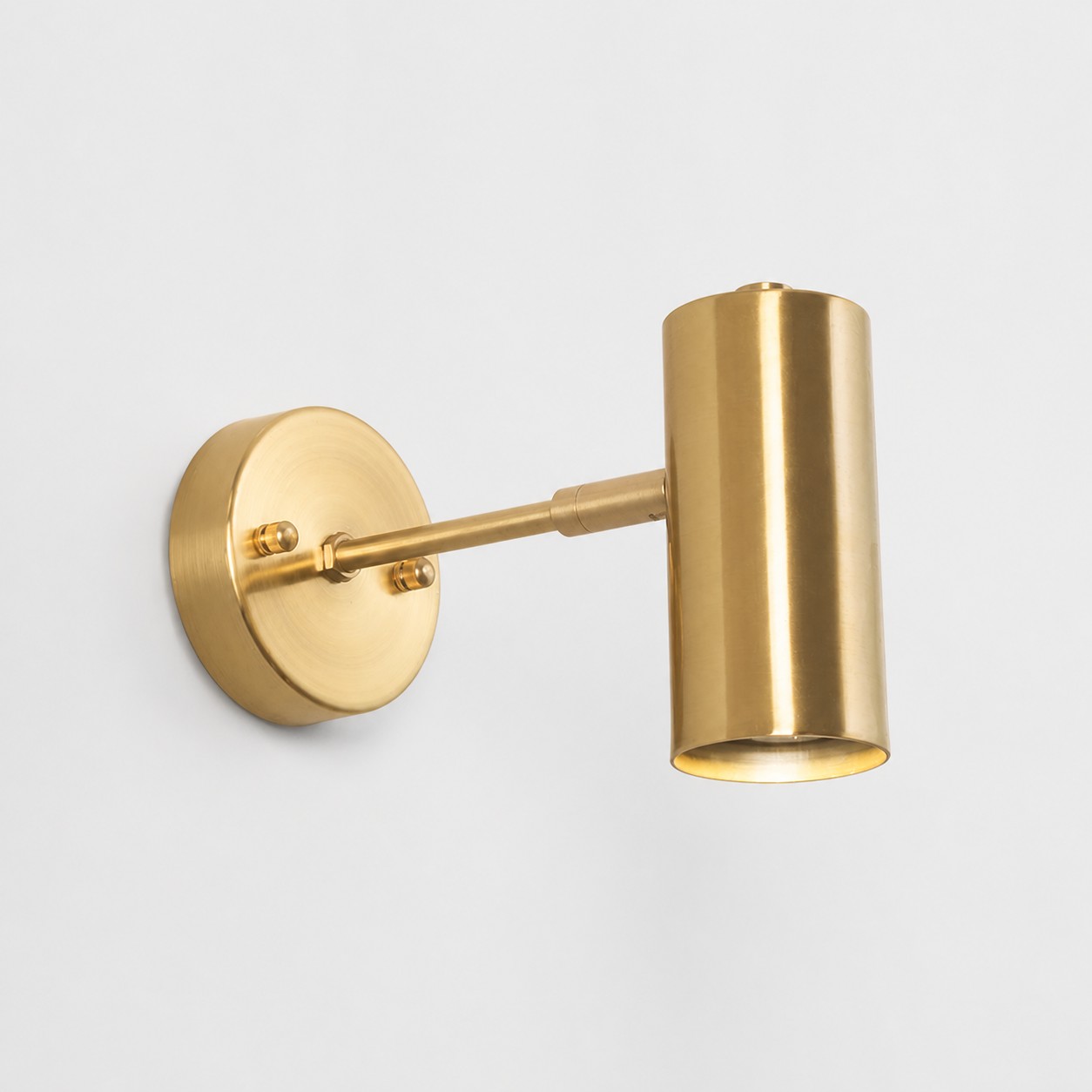 Brushed brass cylinder wall sconce on a white background
