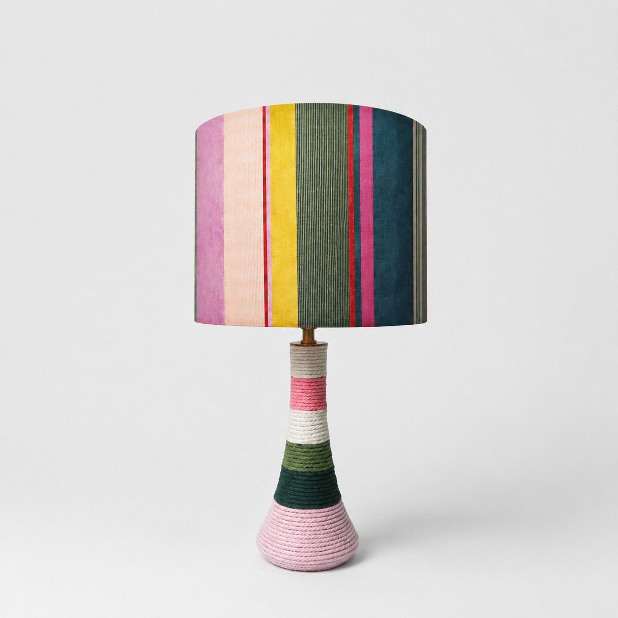 Lampe de table en tissu rayé coloré, avec base recouverte de fil, sur fond blanc