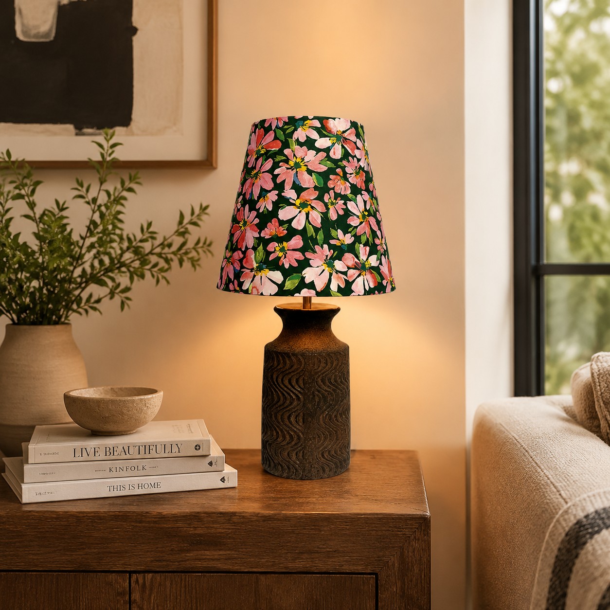 Lámpara de mesa de cerámica floral encendida junto a un sofá sobre una mesa auxiliar de madera