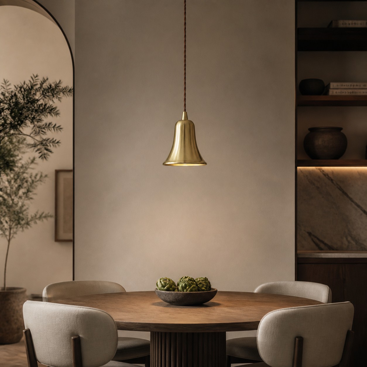 Bell-shaped natural brass pendant light above a warm dining table