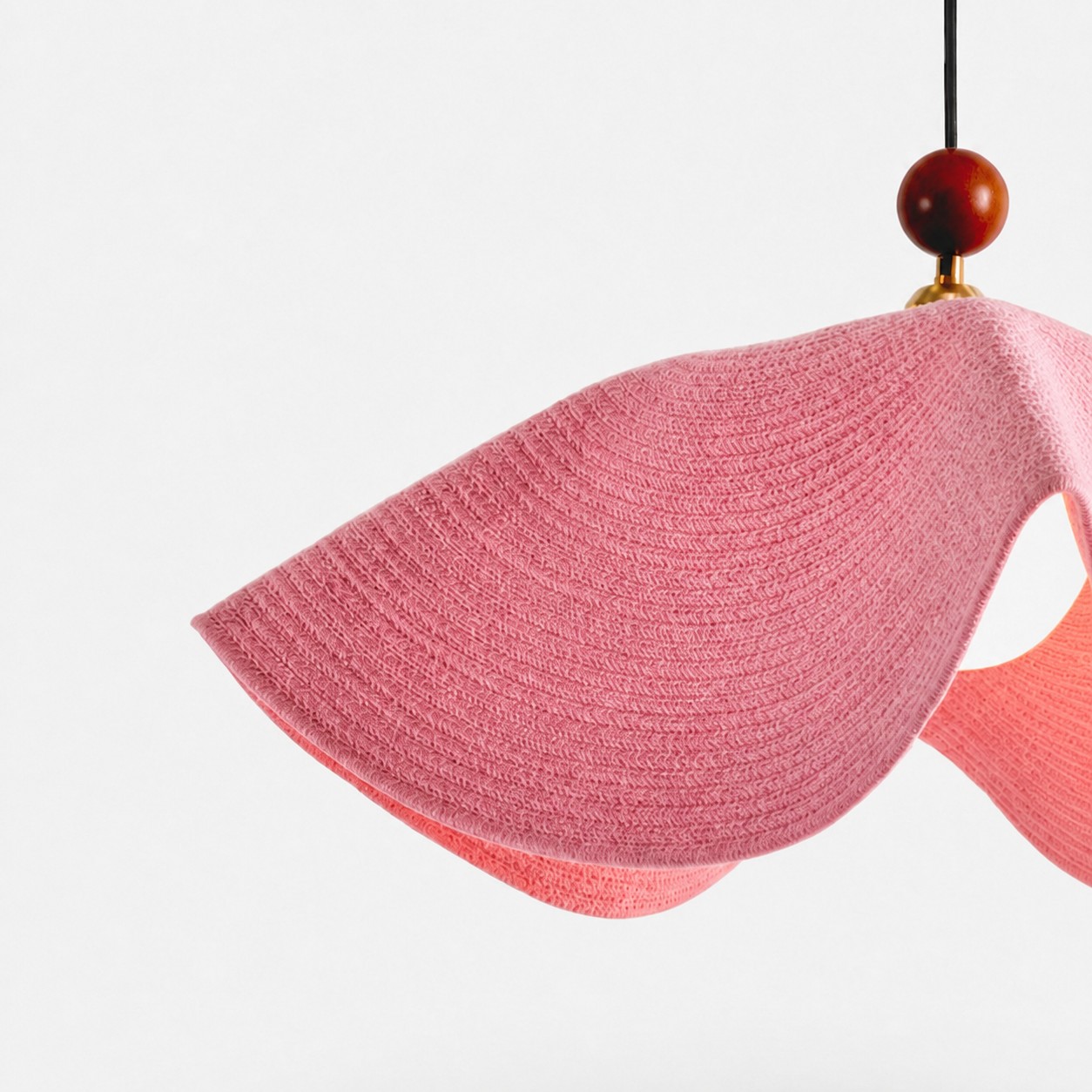 Detailweergave van de roze geweven lampenkap en de zacht gebogen rand.