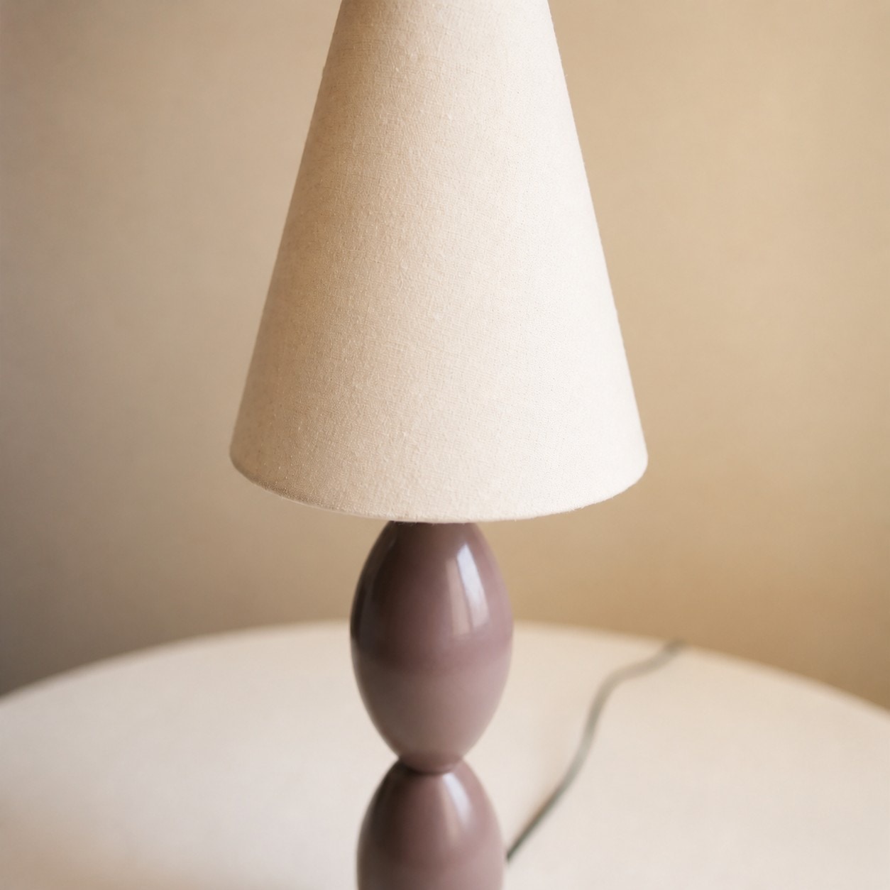 Detailweergave van de gestructureerde stoffen lampenkap en de taupebruine lampvoet.