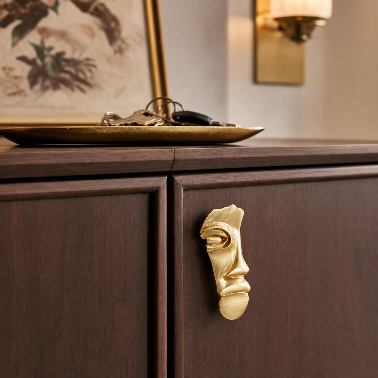 Abstract brass face cabinet knob on dark wood cabinetry