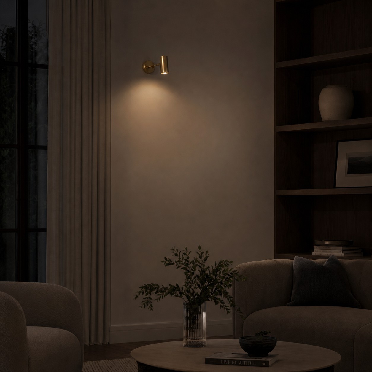 Brass cylinder wall sconce casting downward light in a quiet evening living room