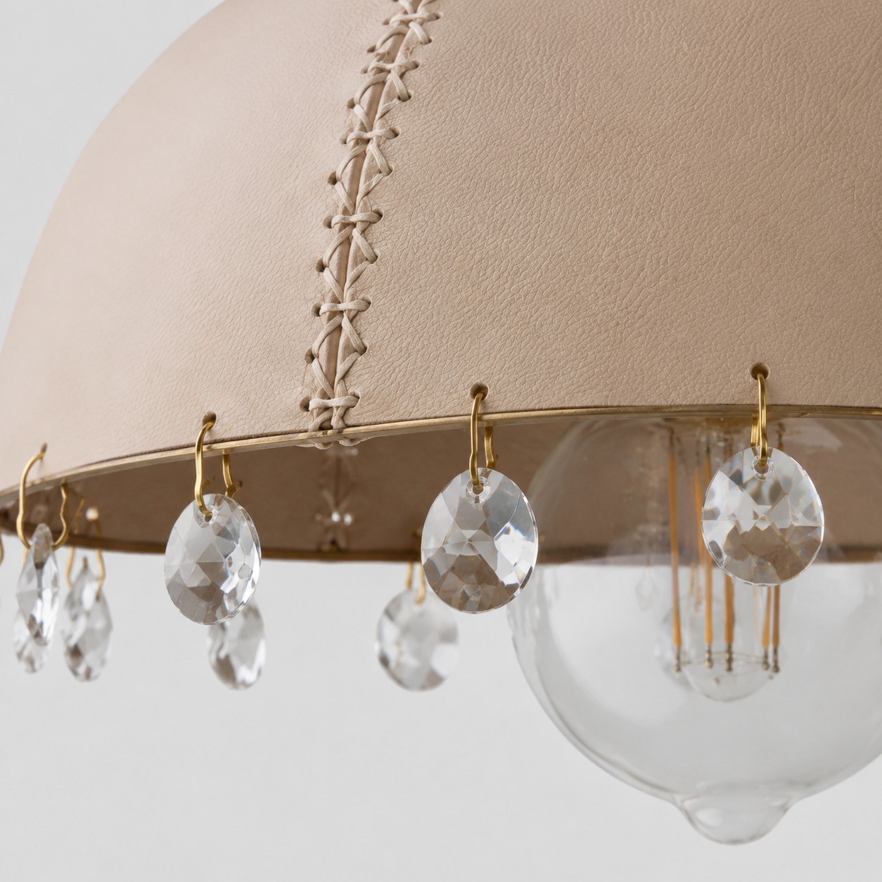 Leather, metal, and crystal details in a compact pendant silhouette