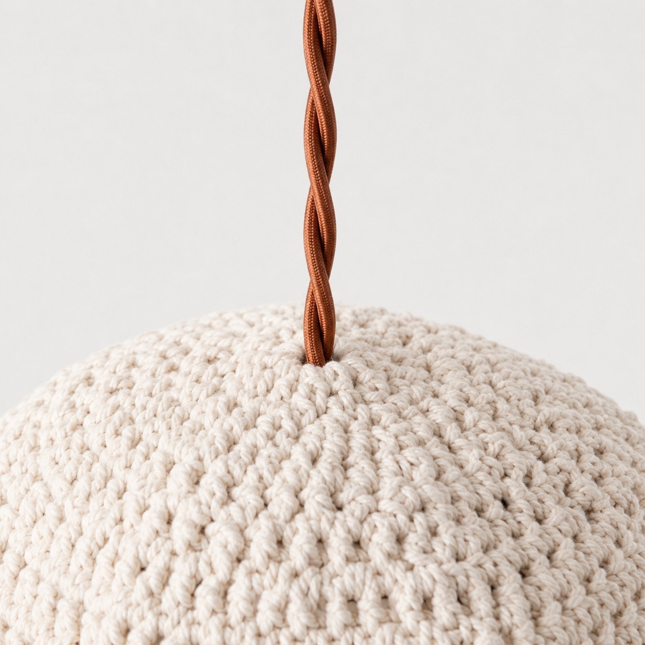 Twisted brown pendant cord entering the ivory handwoven shade
