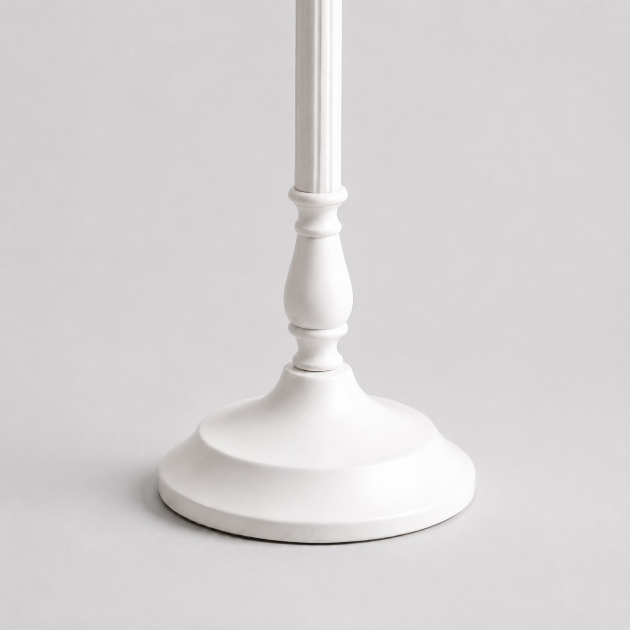 Close-up of scalloped round base on the white metal table lamp
