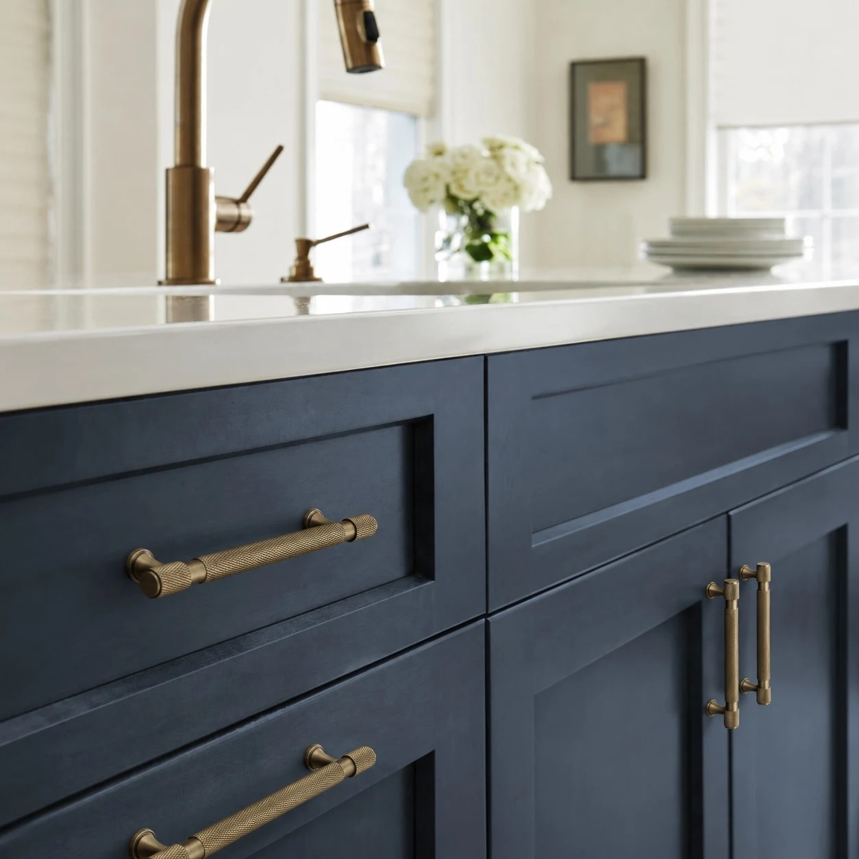 Antique brass pulls installed on blue kitchen cabinetry