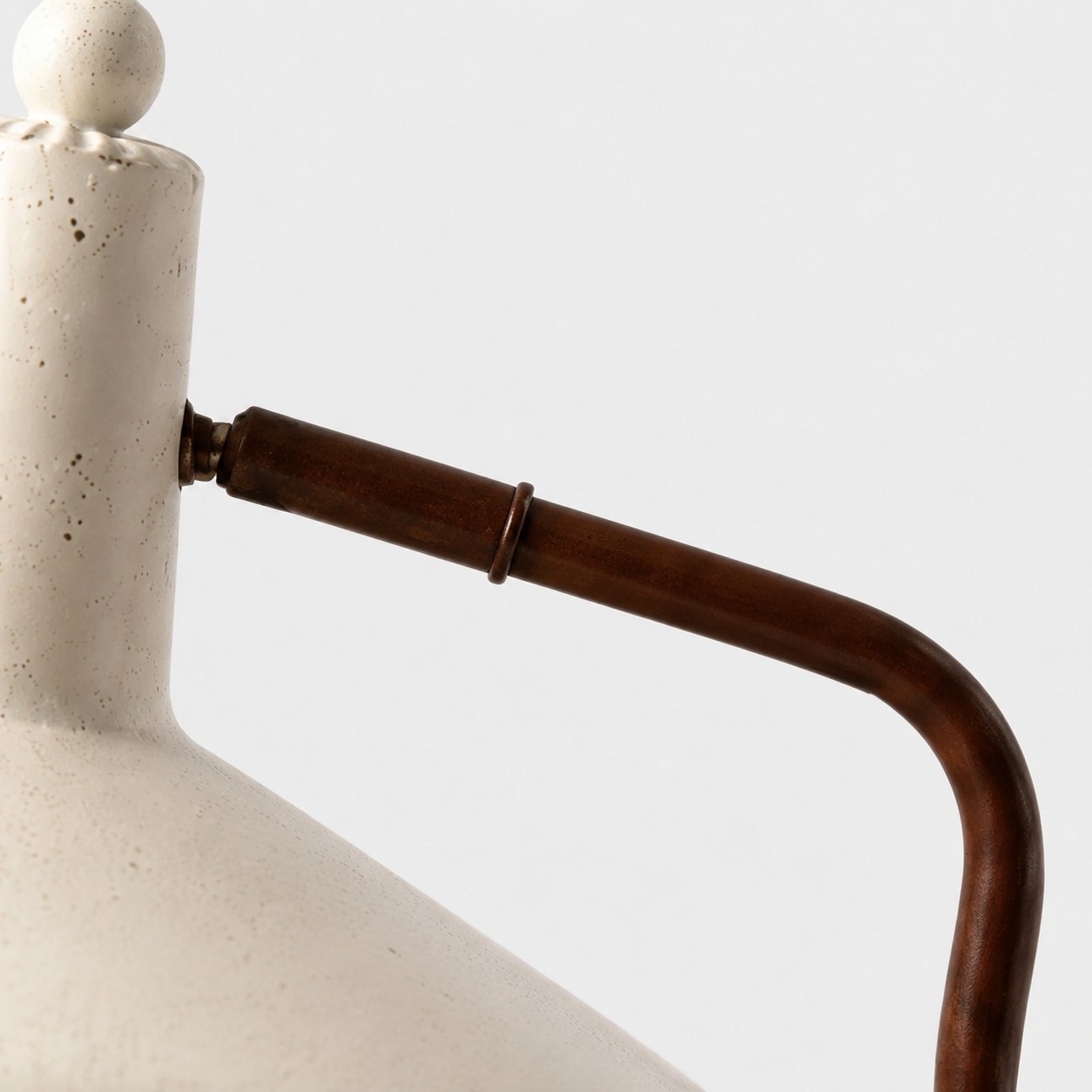 Detailopname van de gebogen bruine ijzeren arm en de verbinding met de lampenkap.