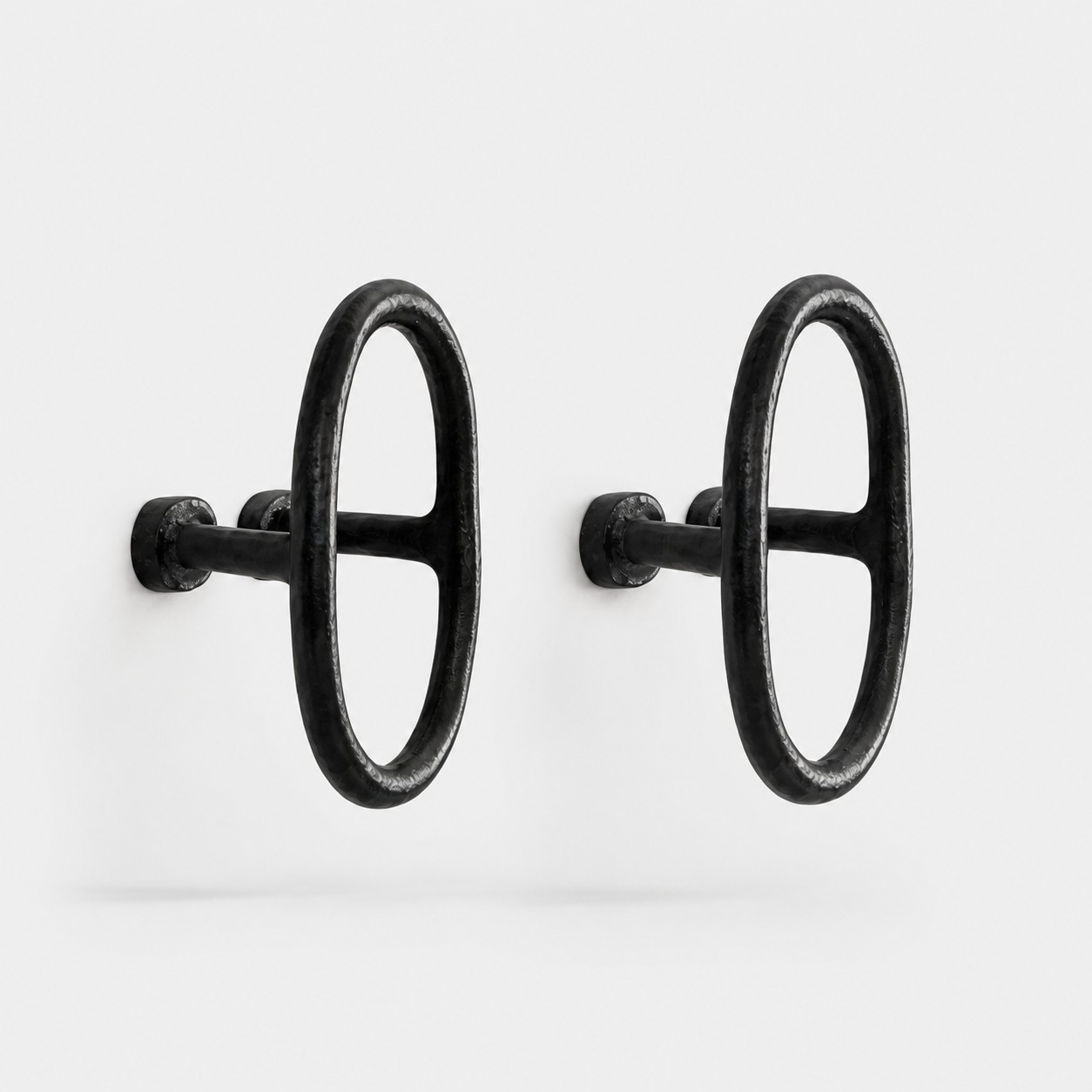 pair of black iron ring cabinet pulls on grey background