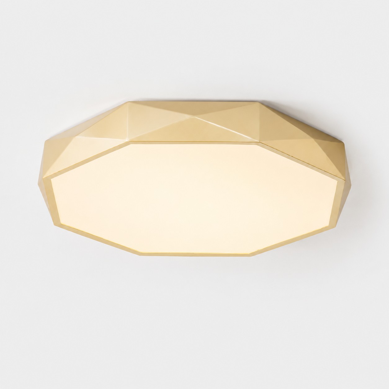 Plafonnier doré à facettes, baigné d'une lumière chaude, vu d'en bas