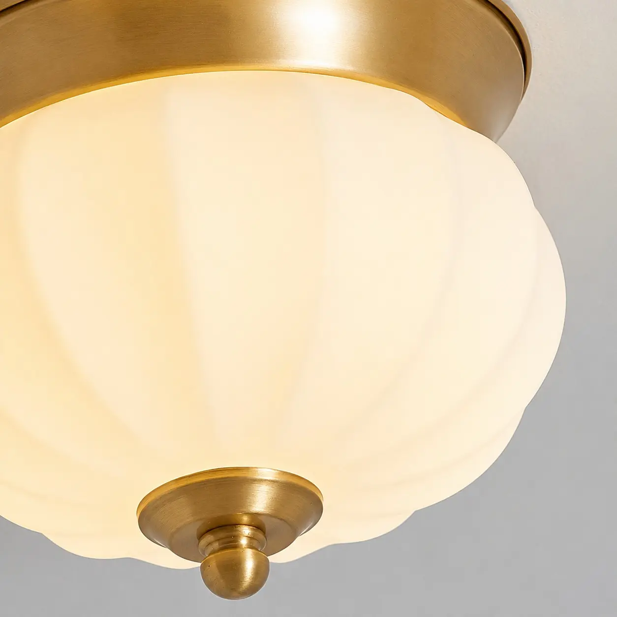 Abat-jour en verre opale illuminé et détail du fleuron en laiton