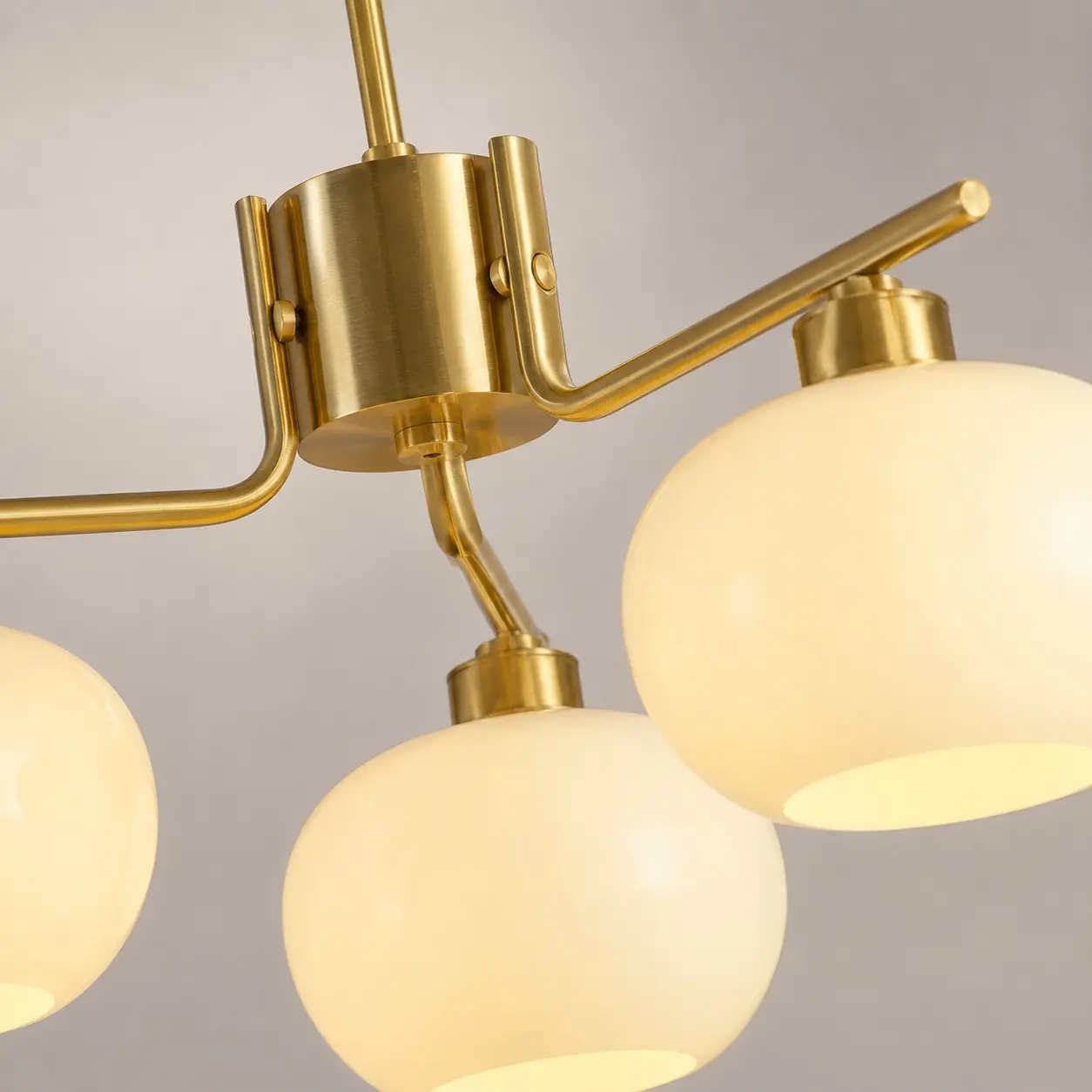 détail de la fixation du bras du lustre en or et de l'abat-jour en verre opalin