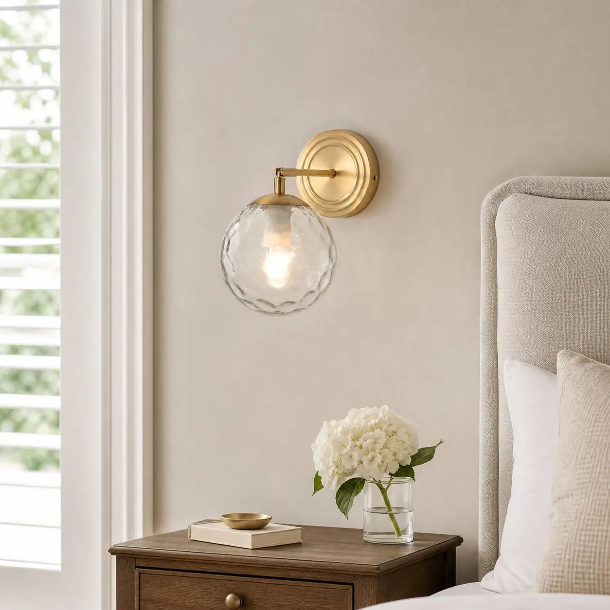 Lampada da parete in vetro ondulato in una camera da letto dai toni neutri e caldi.