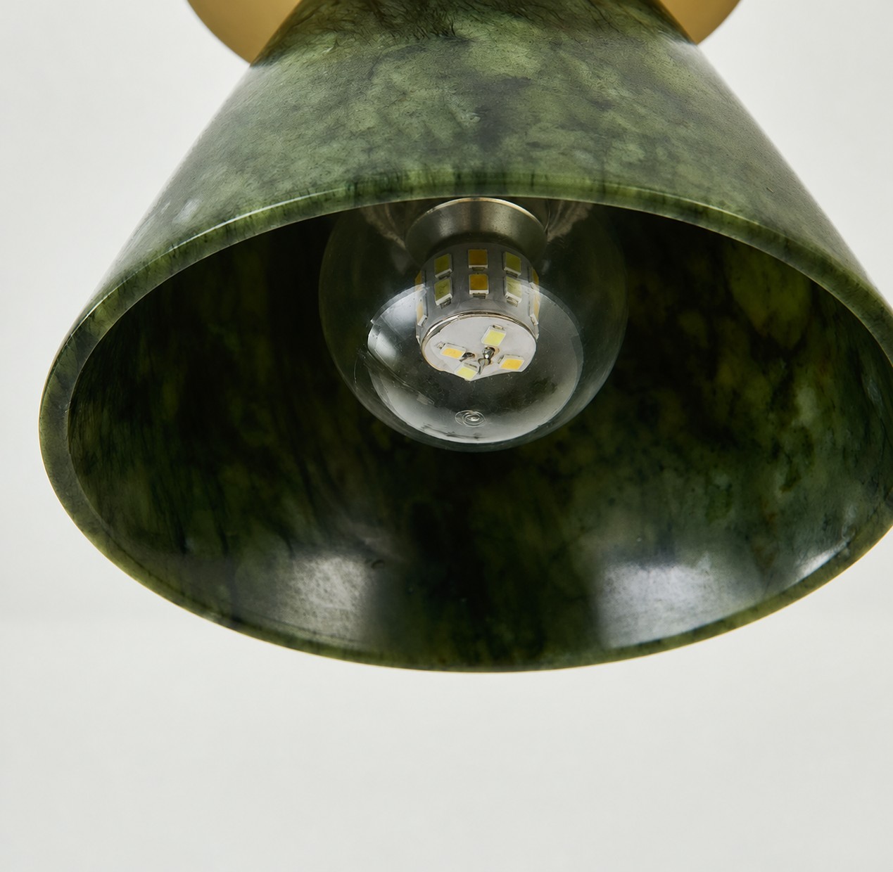 Primer plano lateral de las vetas de la pantalla de jade verde y el aro de latón cepillado