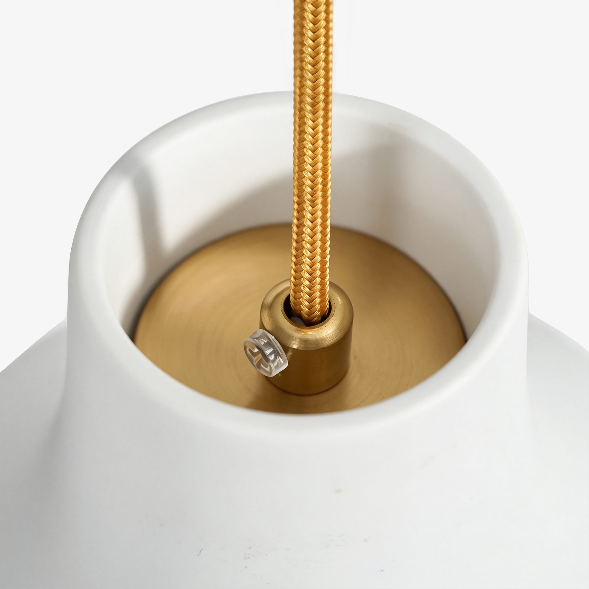 Close-up of braided cord and brass holder on white porcelain shade