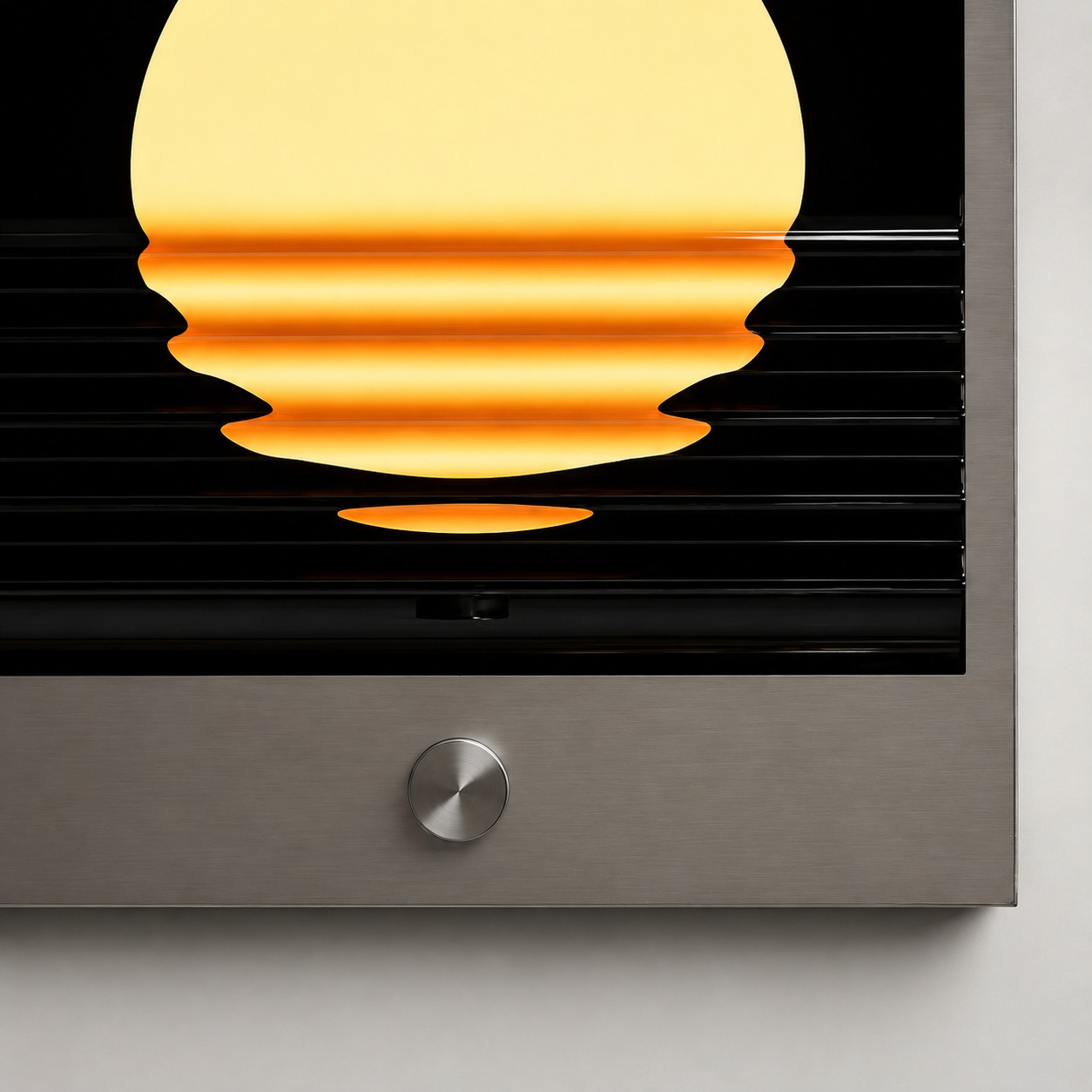 Close-up of brushed-silver frame, control knob, and sunset ripple light effect
