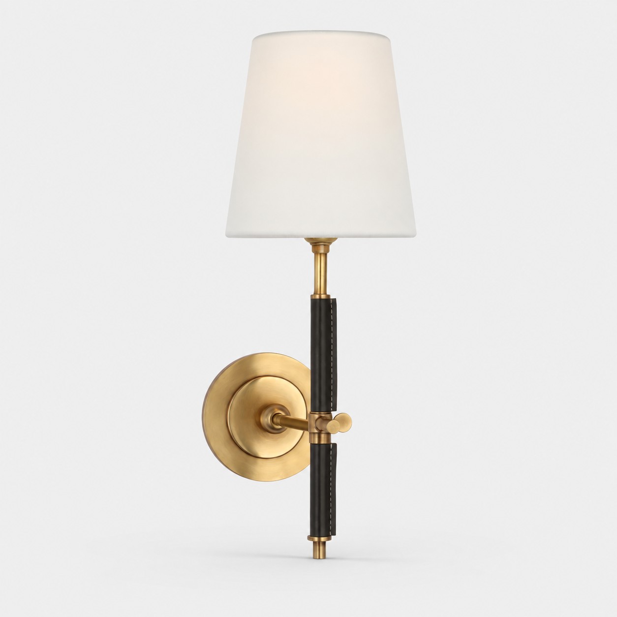 Wandlamp van natuurlijk messing met een kap van zwart leer en witte stof.
