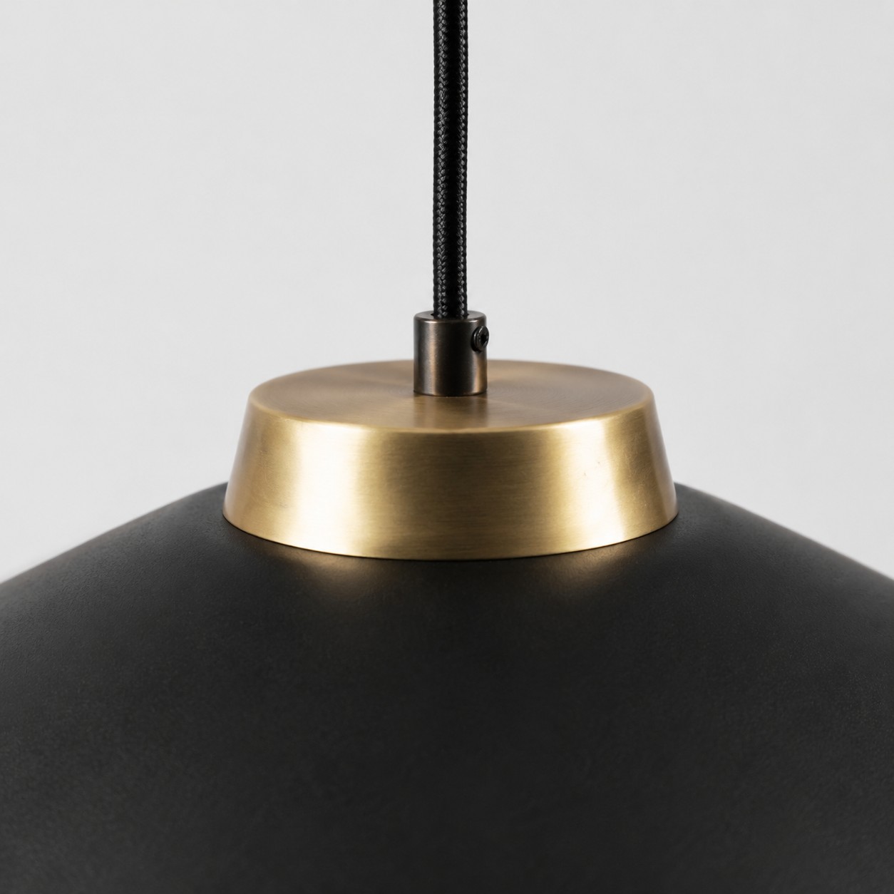 Close view of the black braided cord and brushed brass shade connector