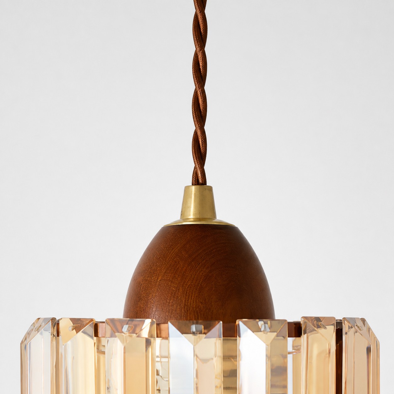 Close view of the twisted suspension cord, wood-toned cap and crystal shade connection