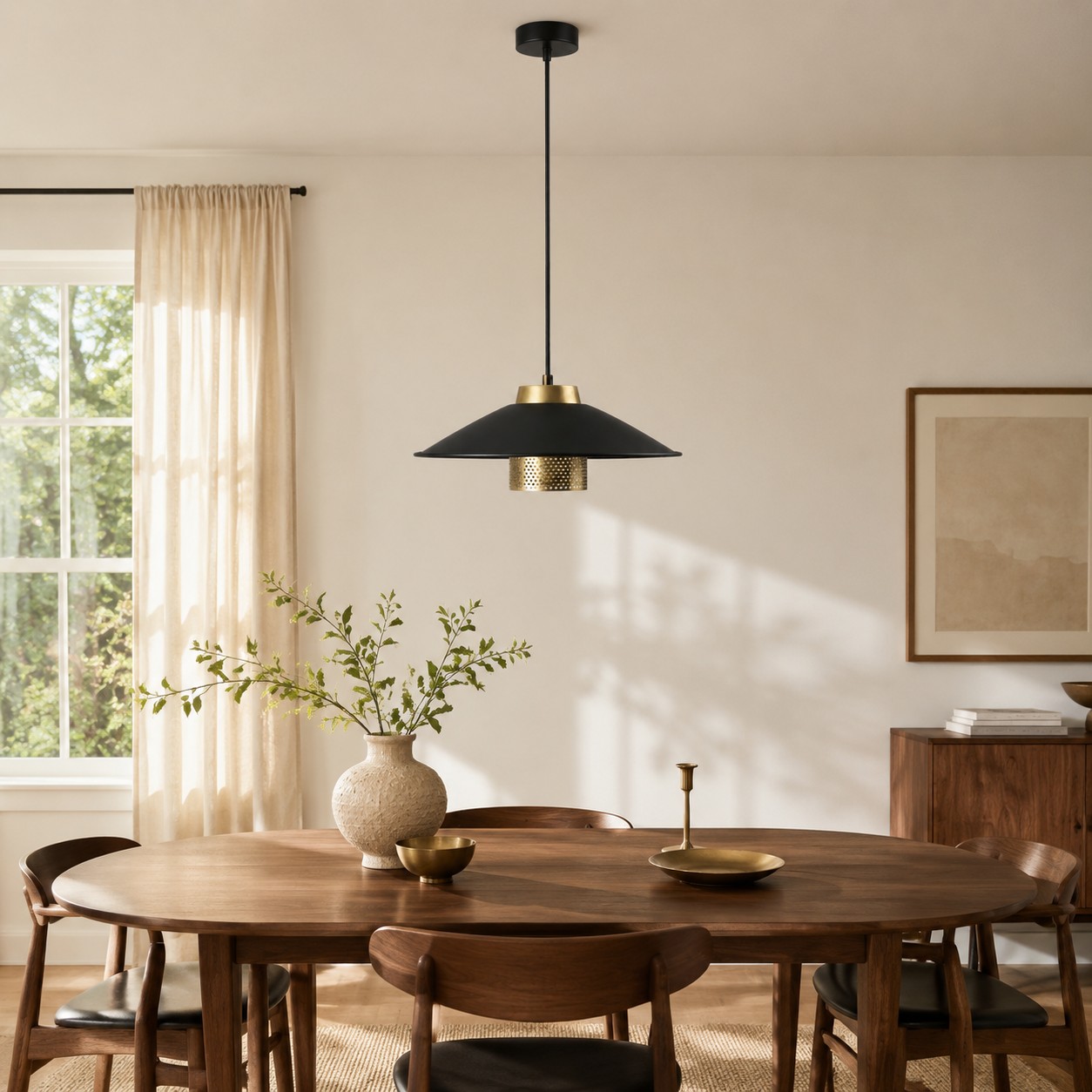 Black and brass pendant light centered above a round walnut dining table