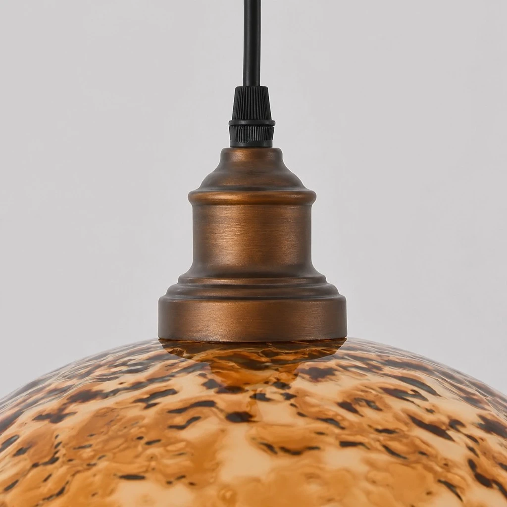 Close view of antique brass socket, black cord, and amber acrylic shade connection