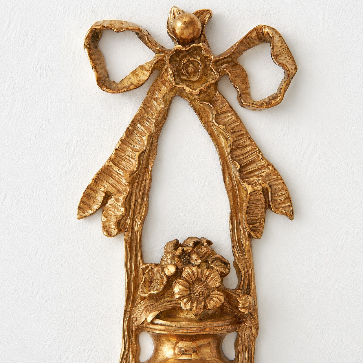 Close view of the ornate brass bow and floral wall plate